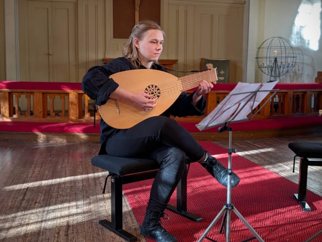 Nainen soittamassa luuttua kirkossa.