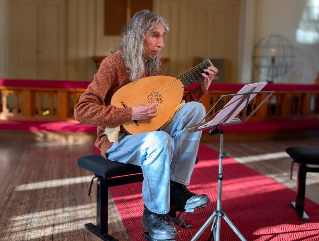 Harmaahiuksinen mies soittamassa luuttua.